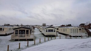 A row of mobile homes with attached porches, set in a snowy landscape.