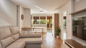 Una sala de estar moderna con un sofá modular, un televisor de pantalla plana y una mesa de comedor de madera.
