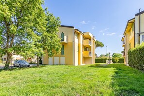 A residential building with a green lawn, a parked car, and a clear blue sky. - Appartamento Le Mimose In Lucca, Lucca, Italy (Lucca)