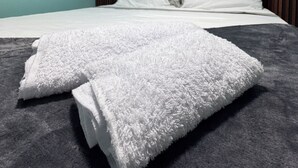 A neatly made bed with white linens and a grey blanket, a wooden headboard, and a teal wall. - Soothing 4-bedroom house with WiFi in Medellín (Medellín)