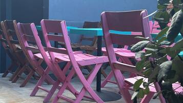 A row of pink folding chairs with a blue table in an outdoor patio area.