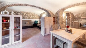 Una cocina rústica con paredes de piedra, armarios de madera y un comedor con mobiliario de mimbre.