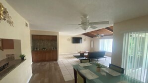 Amplia sala de estar con mesa de comedor de vidrio, sofá y ventilador de techo.
