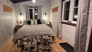 Een slaapkamer met een bed, twee nachtkastjes, een raam en een houten vloer.