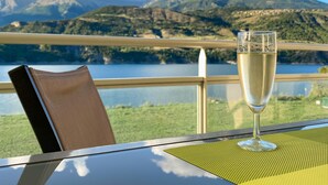Una mesa con una copa de champán, una silla y vistas a un lago y montañas.