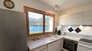Una cocina moderna con un amplio ventanal que ofrece una vista panorámica de montañas y un lago.