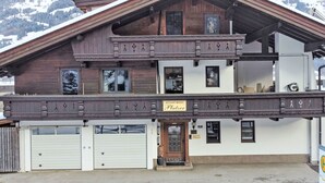Een houten gebouw met twee verdiepingen, een balkon en een garage, met een bord dat het als appartement identificeert.