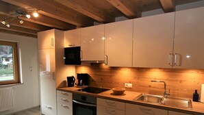 Een moderne keuken met witte kastjes, een ingebouwde oven, een magnetron en een houten aanrecht.