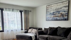 A modern living room with a grey sofa, a round coffee table, and a large abstract painting on the wall. - 2 BR 1 Ba apartment, 2 min walk to Albany Med, w/ off street parking & Washer/D (Albany)
