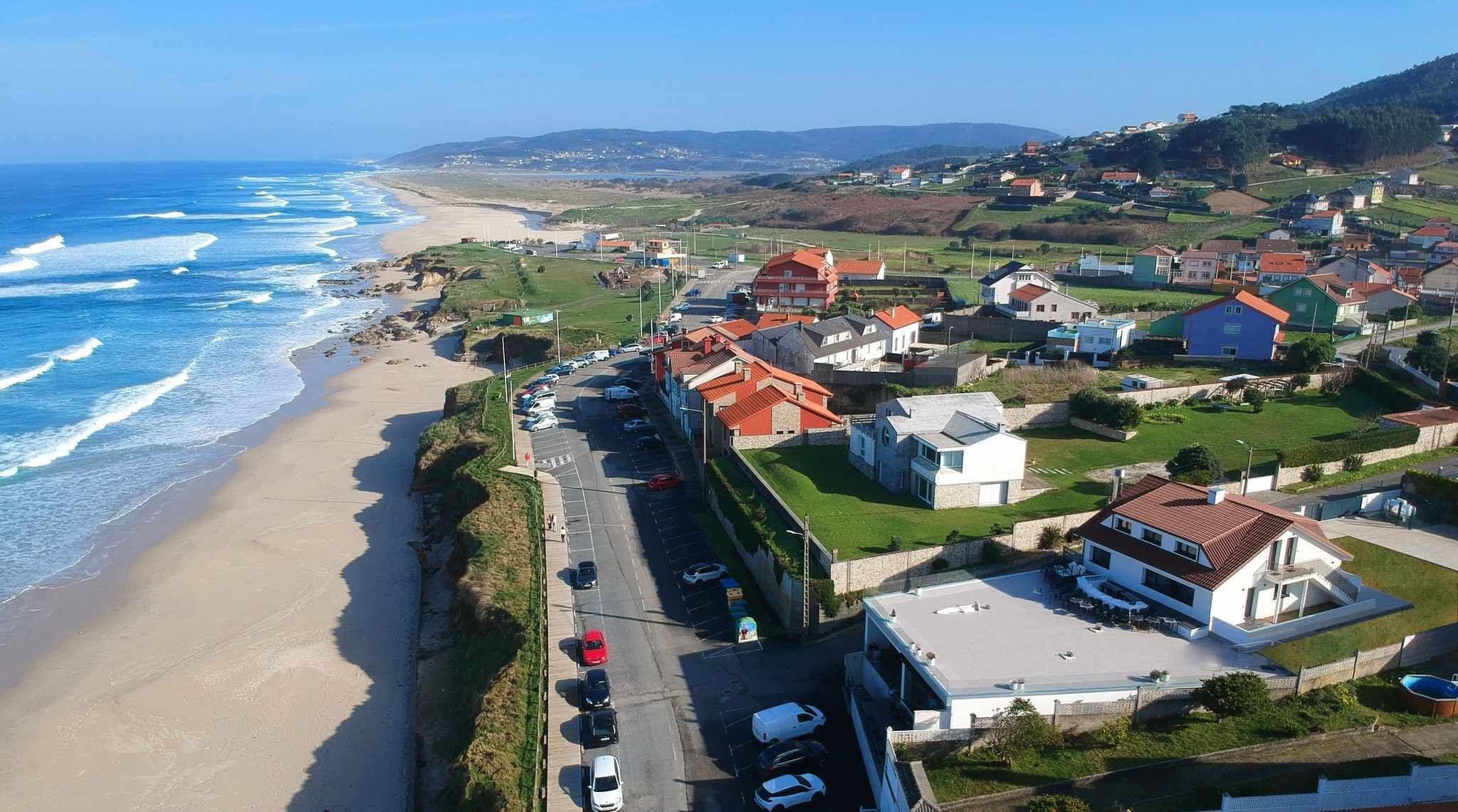 Eine Wohngegend an der Küste mit Häusern, einem Strand und einer Straße.