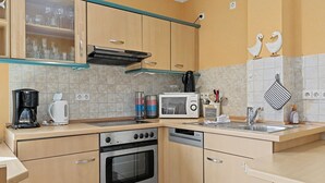 A kitchen with wooden cabinets, a built-in oven, a microwave, and a coffee maker. - Waterkant by Interhome (Zinnowitz)