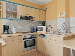A kitchen with wooden cabinets, a built-in oven, a microwave, and a coffee maker.