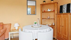 A living room with a round white table, a wooden cabinet, a mirror, and a sofa. - Waterkant by Interhome (Zinnowitz)