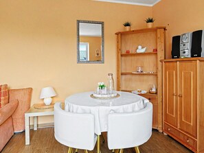 A living room with a round white table, a wooden cabinet, a mirror, and a sofa.