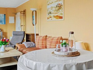 A hotel room with a round table, a sofa, a lamp, and a painting on the wall.