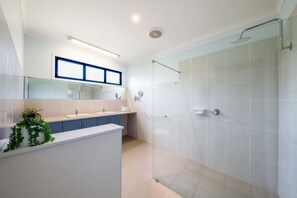 A modern bathroom with a glass shower enclosure, a white sink, and a mirror above the sink.