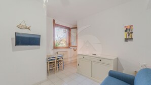 A room with a television, a dining area with chairs, a cabinet, and a window with a view. - APPARTAMENTI LA MARINA - APPARTAMENTI LA MARINA - LIMONI (Marciana Marina)
