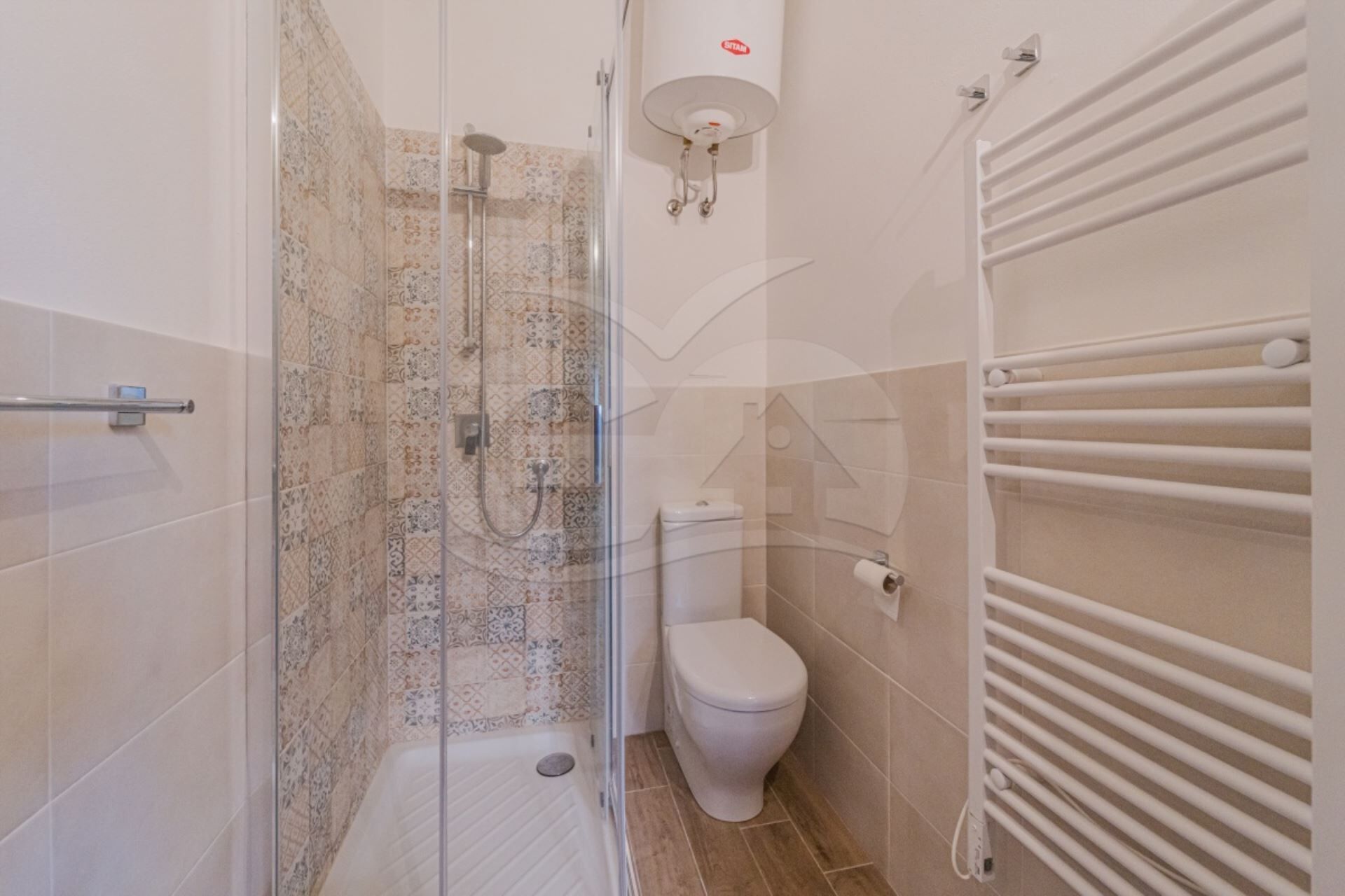 Un baño con ducha, inodoro y barra para toallas.