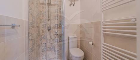Un baño con ducha, inodoro y barra para toallas.