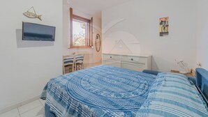 A bedroom with a bed, a TV, a dresser, a chair, and a window. - APPARTAMENTI LA MARINA - APPARTAMENTI LA MARINA - LIMONI (Marciana Marina)