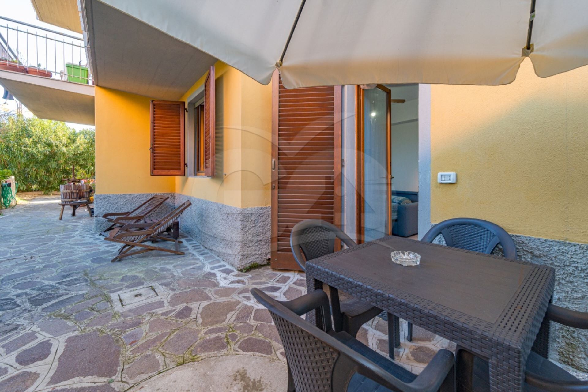 An outdoor patio with a table and chairs, a wooden bench, and a covered area with a white canopy.