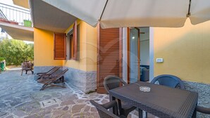 An outdoor patio with a table and chairs, a wooden bench, and a covered area with a white canopy. - APPARTAMENTI LA MARINA - APPARTAMENTI LA MARINA - LIMONI (Marciana Marina)