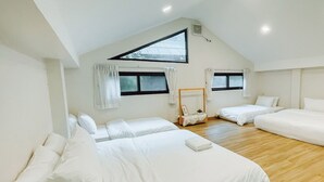 A spacious, well-lit attic bedroom with three beds arranged in a U-shape, wooden flooring, and a skylight. - My Cottage Chiangmai (Mae On)