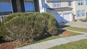 A residential house with a brick facade, a well-maintained lawn, and a stone pathway leading to the front door.