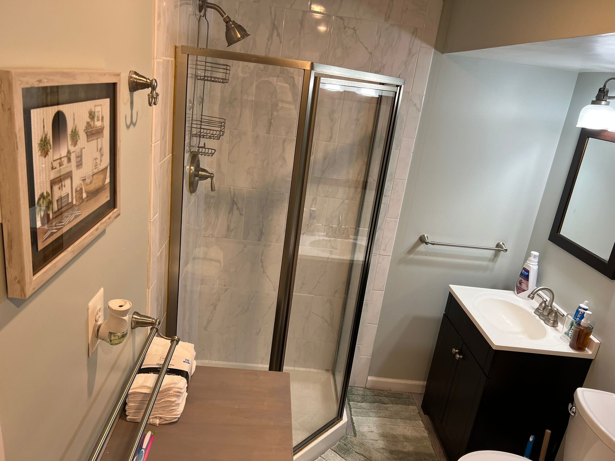 Une salle de bain moderne avec une douche à parois de verre, un lavabo avec un miroir et un porte-serviettes.