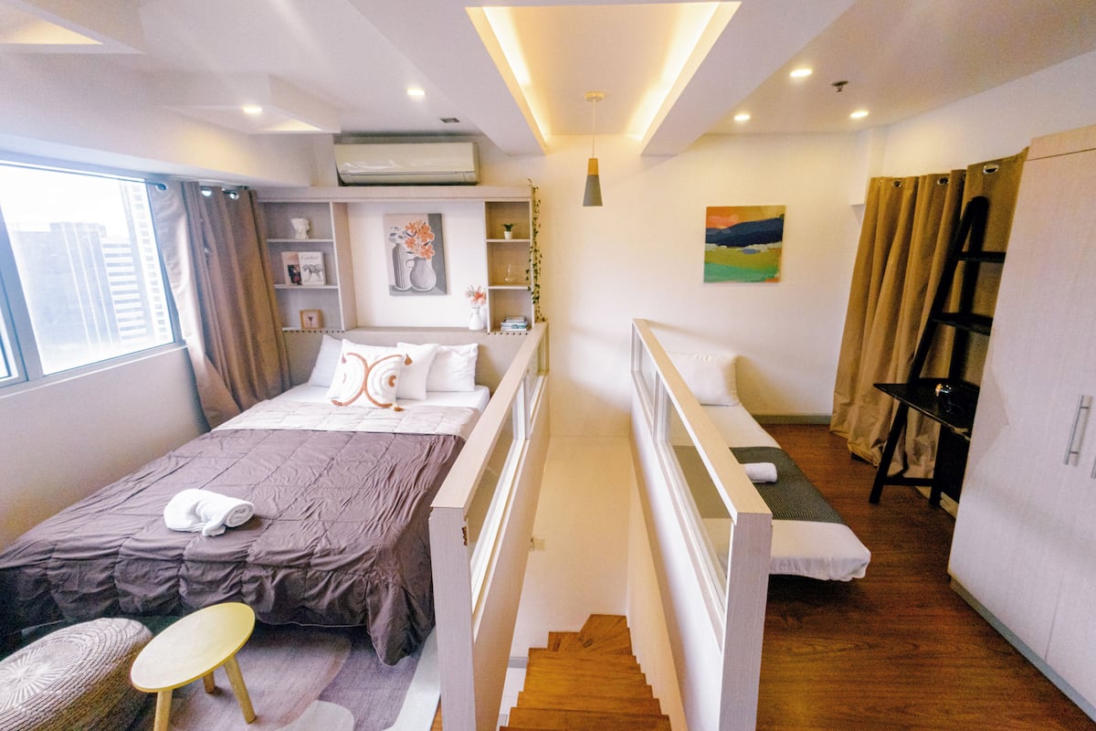 A hotel room with a bed, a desk, a chair, a wardrobe, and a window.