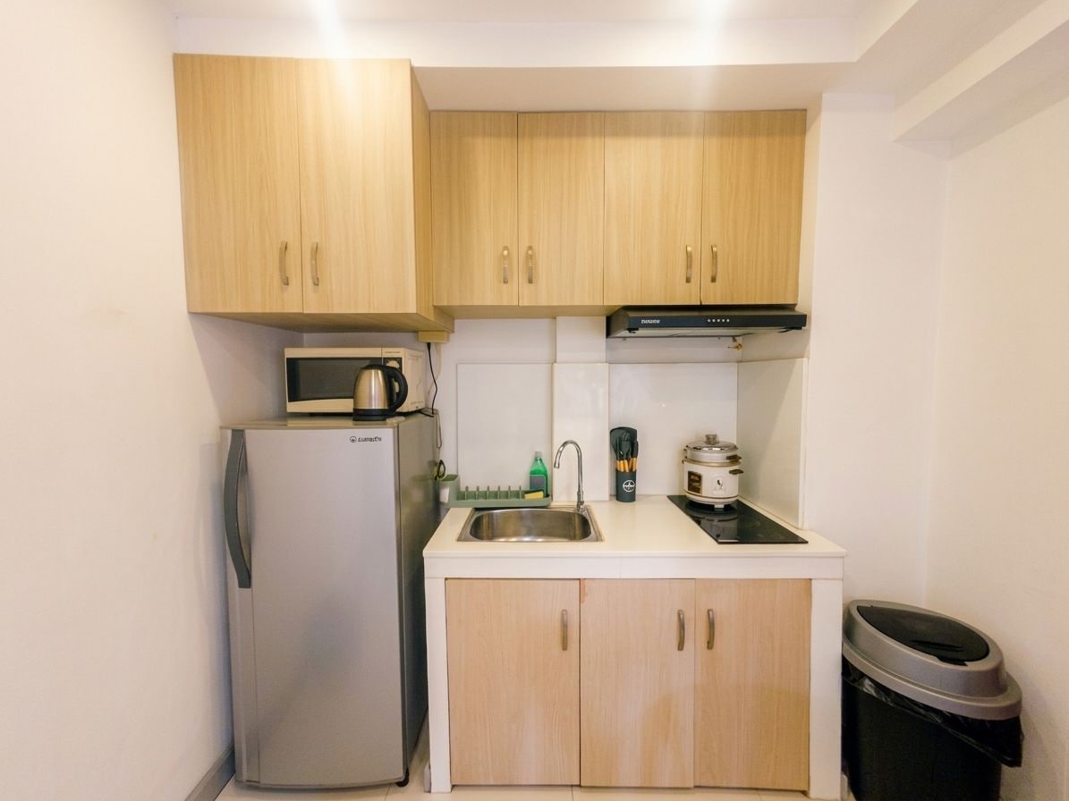 A compact kitchen with a refrigerator, microwave, stove, and sink.