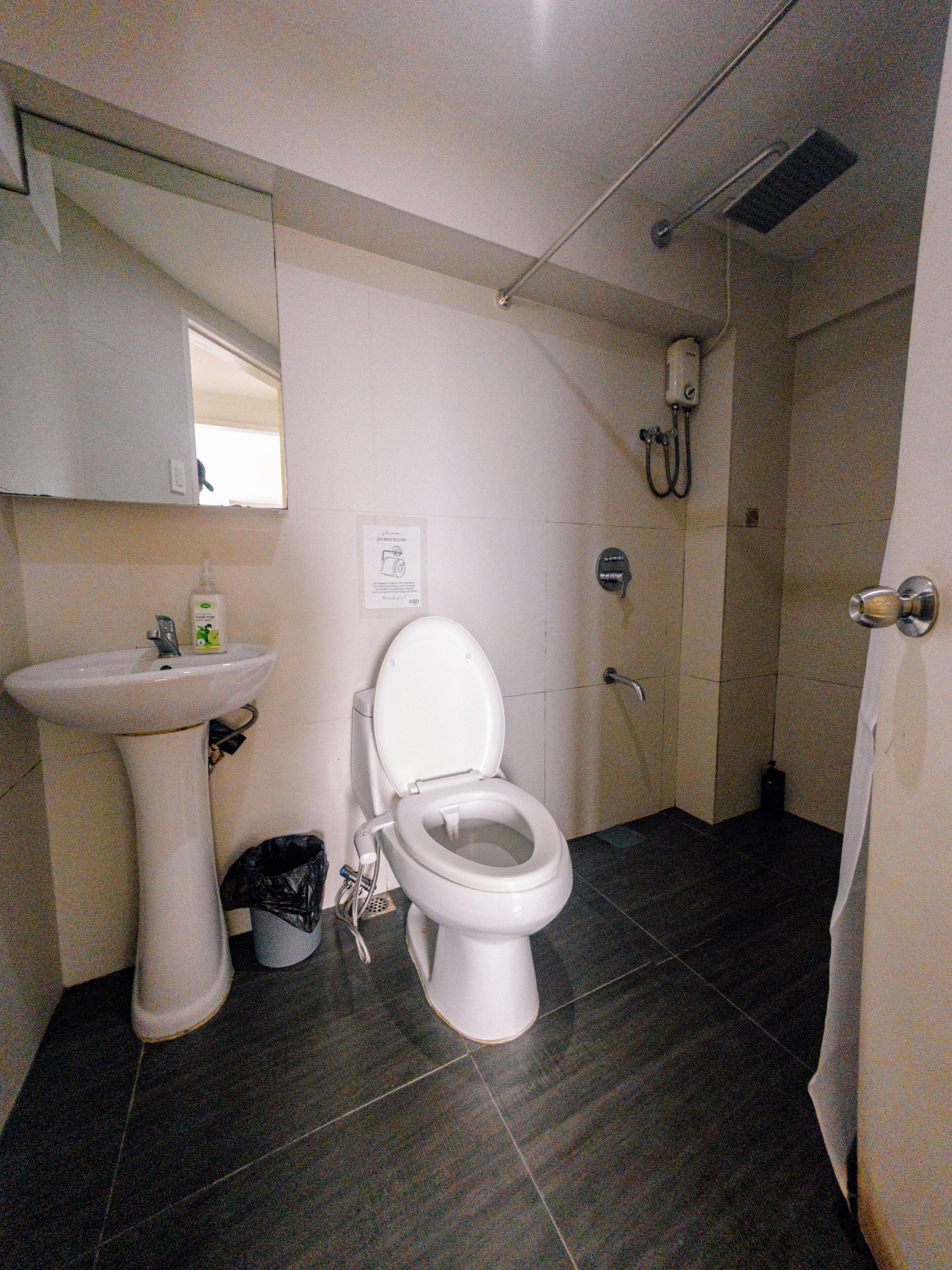 A bathroom with a toilet, sink, and shower.