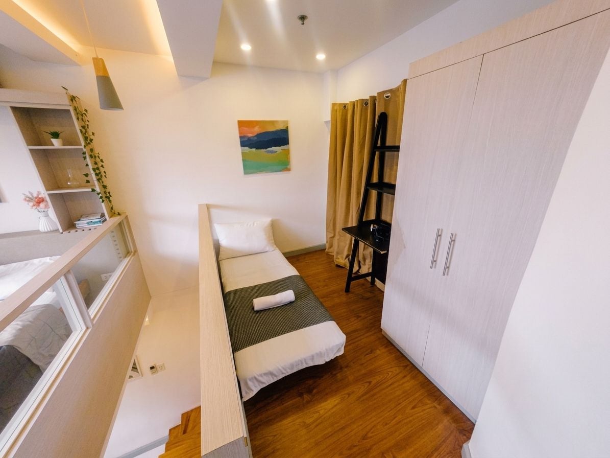 Ein gemütliches Schlafzimmer mit Bett, Kleiderschrank, Schreibtisch und einem Regal mit Pflanzen.