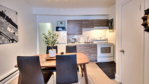 A compact kitchen with modern appliances, a dining area with a table and chairs, and a potted plant.