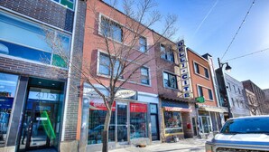 A street view with a brick building, storefronts, and a parked vehicle.