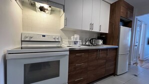 A modern kitchen with white appliances, wooden cabinets, and a tiled backsplash. - Stylish 1 Bedroom in Saint-Laurent (Montréal)