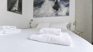 A neatly made bed with white linens and two folded towels.