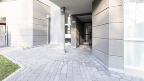 Un bâtiment moderne avec une façade contemporaine, un trottoir dallé et une entrée avec une porte en verre.
