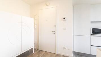 A modern kitchen with white cabinetry, a microwave, and a door with a handle.
