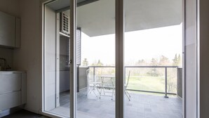 Un appartement moderne doté d’une porte-fenêtre coulissante donnant sur un balcon avec une table et des chaises.