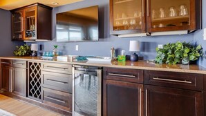 A modern kitchen with dark wood cabinets, a stainless steel dishwasher, and a built-in oven. - The Tubac Alegria Retreat (Tubac)