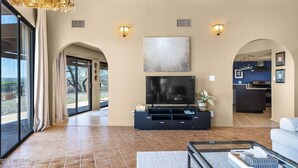 A spacious living room with a large flat-screen TV, a dark entertainment unit, and a glass coffee table. - The Tubac Alegria Retreat (Tubac)