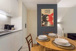 A modern kitchen with a dining area, a poster on the wall, and a TV.