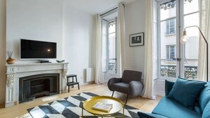 Un salon avec une cheminée, un canapé, une table basse et un téléviseur.