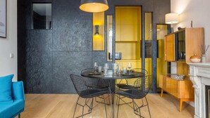 Un espace repas moderne avec une table ronde, des chaises à armature métallique noire et un luminaire suspendu.