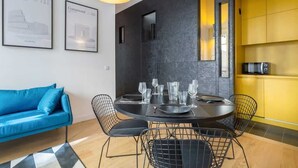 Un espace repas moderne avec une table ronde, des chaises noires et un buffet jaune en arrière-plan.