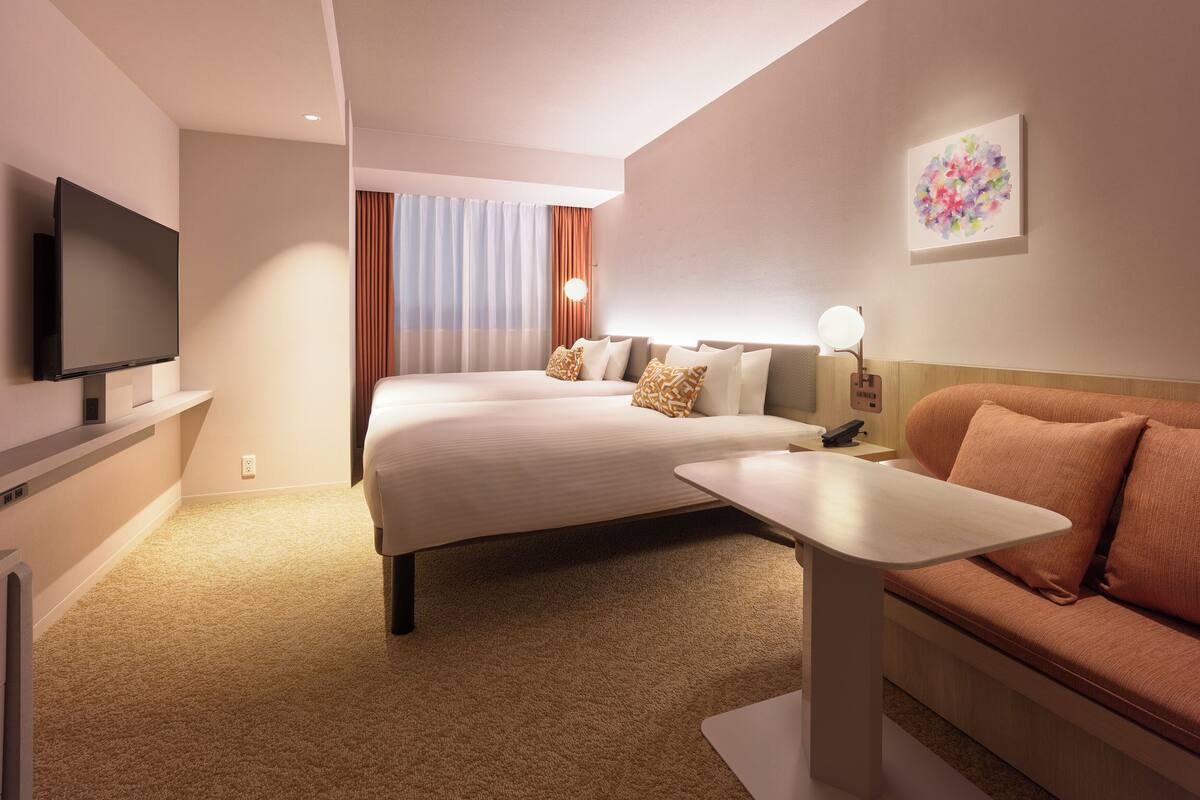 A hotel room with a bed, a TV, a desk, and a couch.