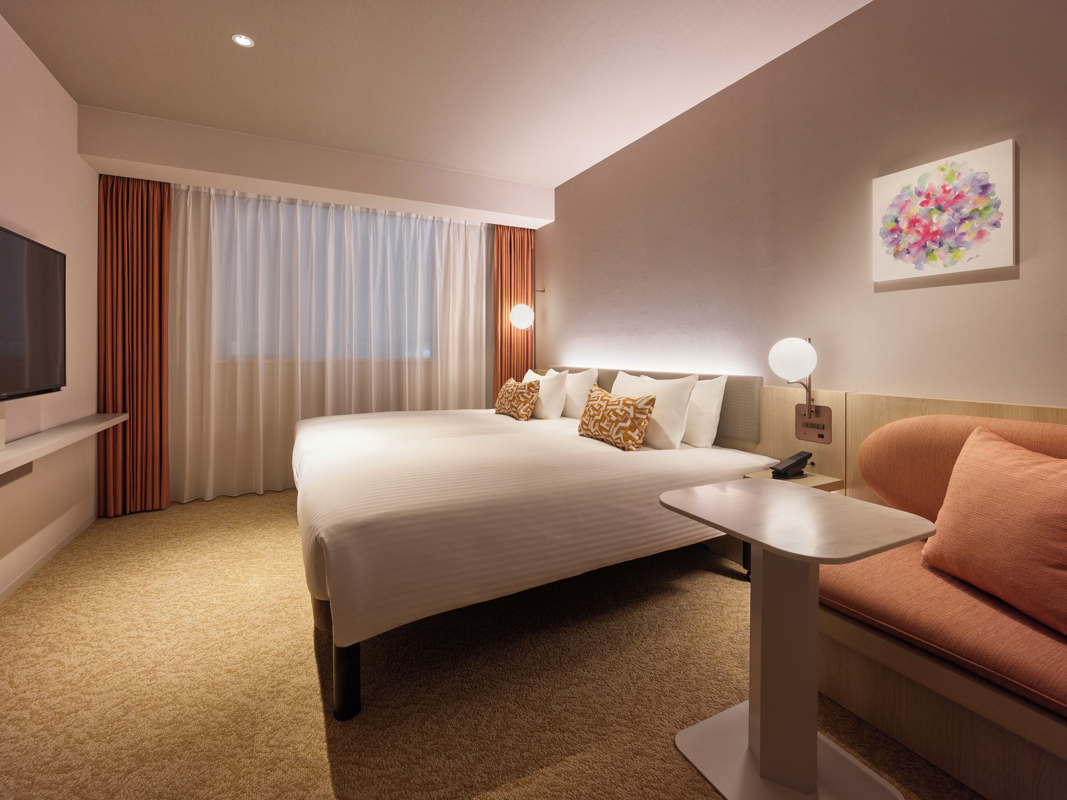 A hotel room with a large bed, a bedside table, a TV, and a painting on the wall.