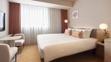 Een hotelkamer met een bed, een bureau, een stoel, een nachtkastje en een lamp.