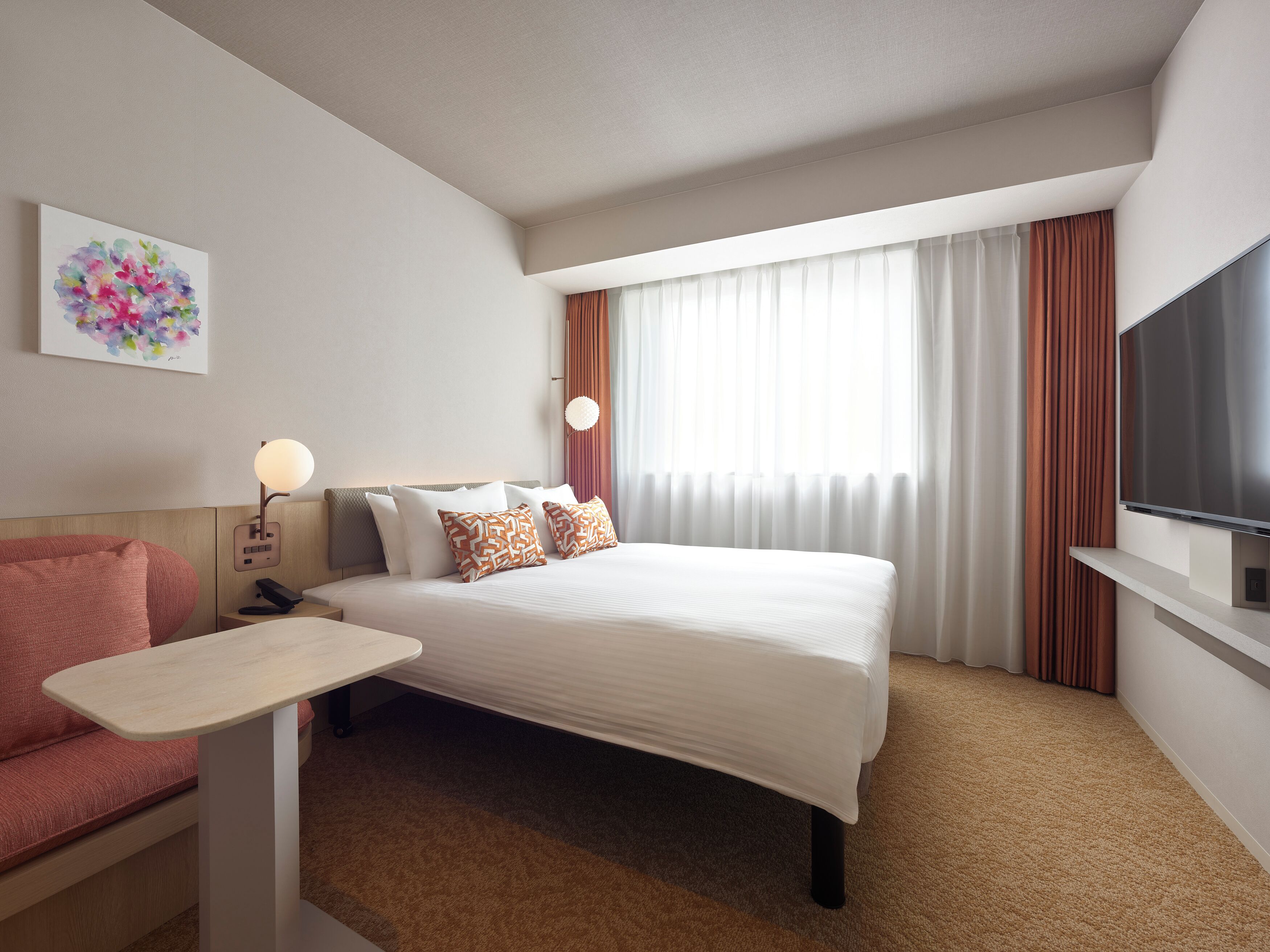 A hotel room with a bed, a desk, a TV, and a painting on the wall.